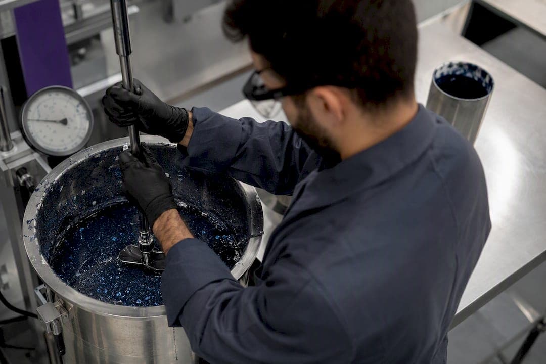 Technician operating low shear paddle mixer in pigment dispersion