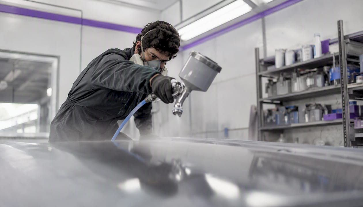Technician spraying clearcoat mist coat on panel